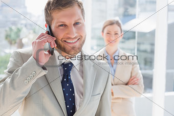 Businessman having phone conversation and smiling at camera