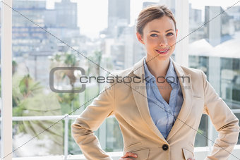 Pretty businesswoman smiling at camera with hands on hips