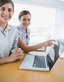 Businesswoman pointing to something on laptop for colleague portrait
