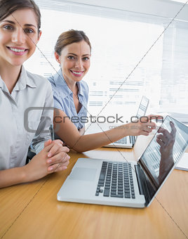 Businesswoman pointing to something on laptop for colleague portrait