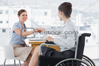 Businesswoman shaking hands with disabled colleague