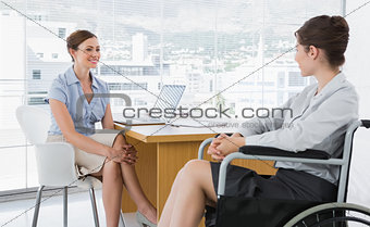 Businesswoman chatting with disabled colleague