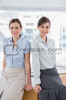 Businesswomen leaning on desk
