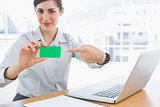 Young businesswoman pointing to green business card