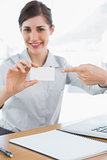 Happy businesswoman pointing to blank business card