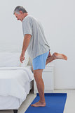 Mature man stretching his leg on an aerobic mat