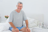 Man smiling while he is sitting on bed