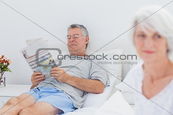 Mature man reading a newspaper in bed