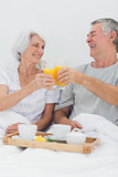 Cheerful couple clinking their orange juice glasses