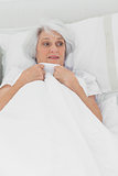 Woman looking afraid in her bed
