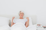 Woman stretching and raising arms in bed