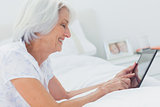 Woman using a tablet while she is lying on bed