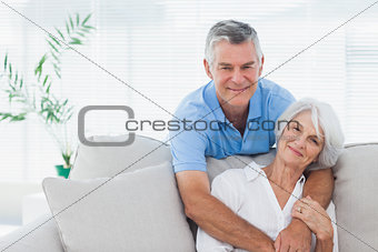 Man embracing wife who is sitting on the couch