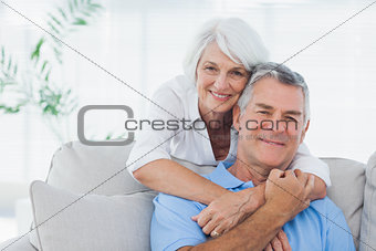 Woman embracing husband sitting on the couch