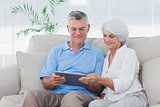 Couple using a tablet sitting on the couch