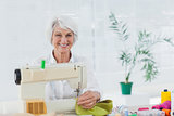 Cheerful woman using the sewing machine at home