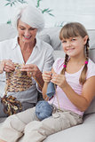 Portrait of a little girl and her granddaughter knitting together