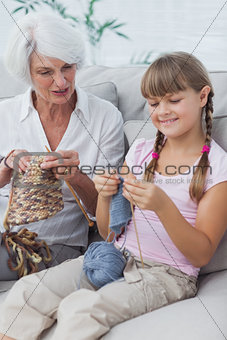 Little girl and her granddaughter knitting together