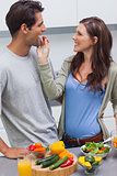 Attractive woman feeding her husband cherry tomato