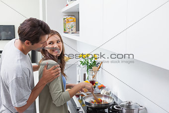 Smiling man looking at his wife who is cooking vegetables