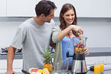 Couple putting fruits into blender