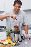 Man putting a strawberry in the blender