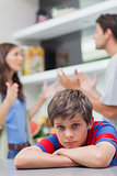Sad little boy listening to his parents arguing