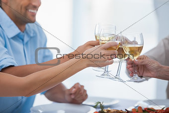 Close up of hands clinking glasses of white wine