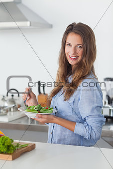 Woman in the kitchen holding a salad bowl