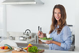 Woman in the kitchen holding a salad bowl with lettuce