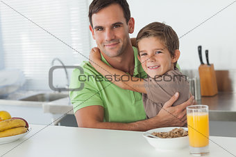 Son embracing his father while having breakfast