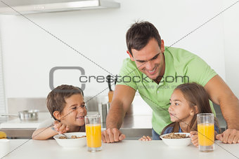 Father chatting to his children while they are having breakfast