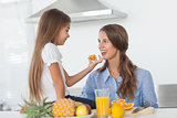 Little girl giving an orange segment to her mother