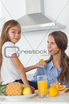 Cute girl giving an orange segment to her mother