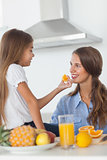 Young girl giving an orange segment to her mother