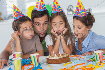 Family blowing candles together