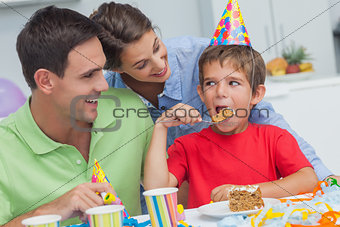 Little boy eating a birthday cake with parents