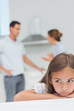 Upset little girl listening to parents who are arguing