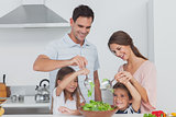 Family mixing a salad together