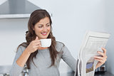 Woman with a cup of coffee reading a newspaper
