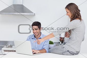 Wife pointing at the laptop of her husband