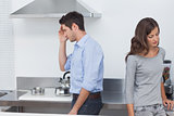 Couple sulking at each other in the kitchen