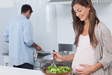 Pregnant woman mixing a salad in the kitchen