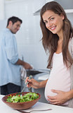 Pregnant woman preparing a salad in the kitchen