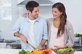 Man chopping vegetables next to his pregnant partner