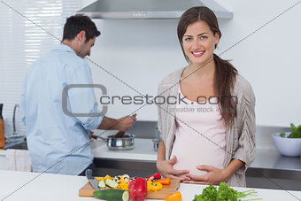 Pregnant woman holding her belly in the kitchen