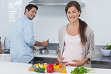 Cheerful pregnant woman holding her belly in the kitchen