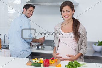 Cheerful pregnant woman holding her belly in the kitchen