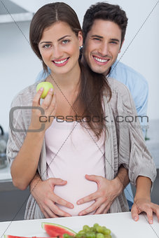 Cheerful man holding the belly of his pregnant wife