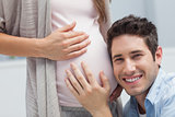 Man listening to the belly of his pregnant wife
